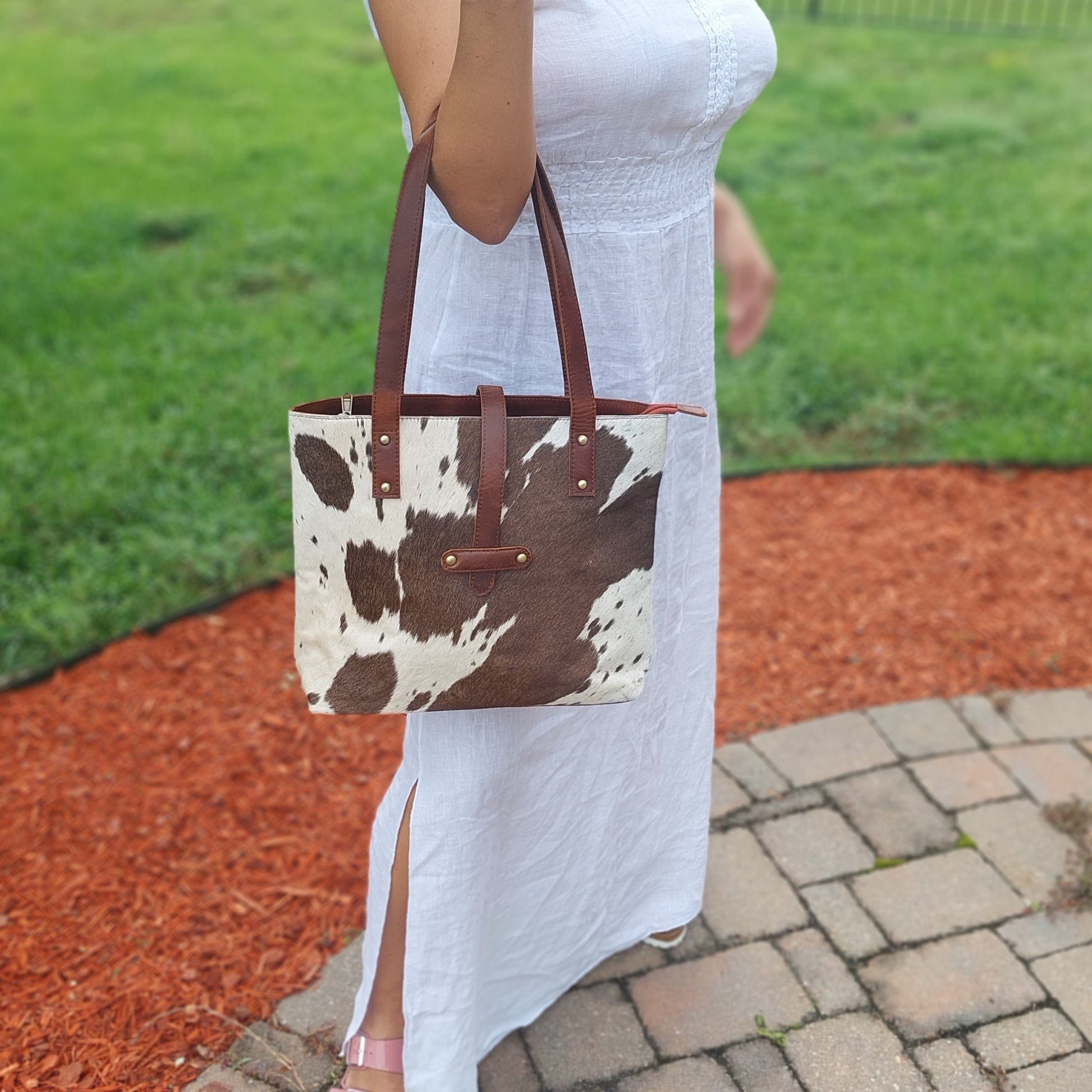 lady holding cowhide and leather handbag on crook of arm